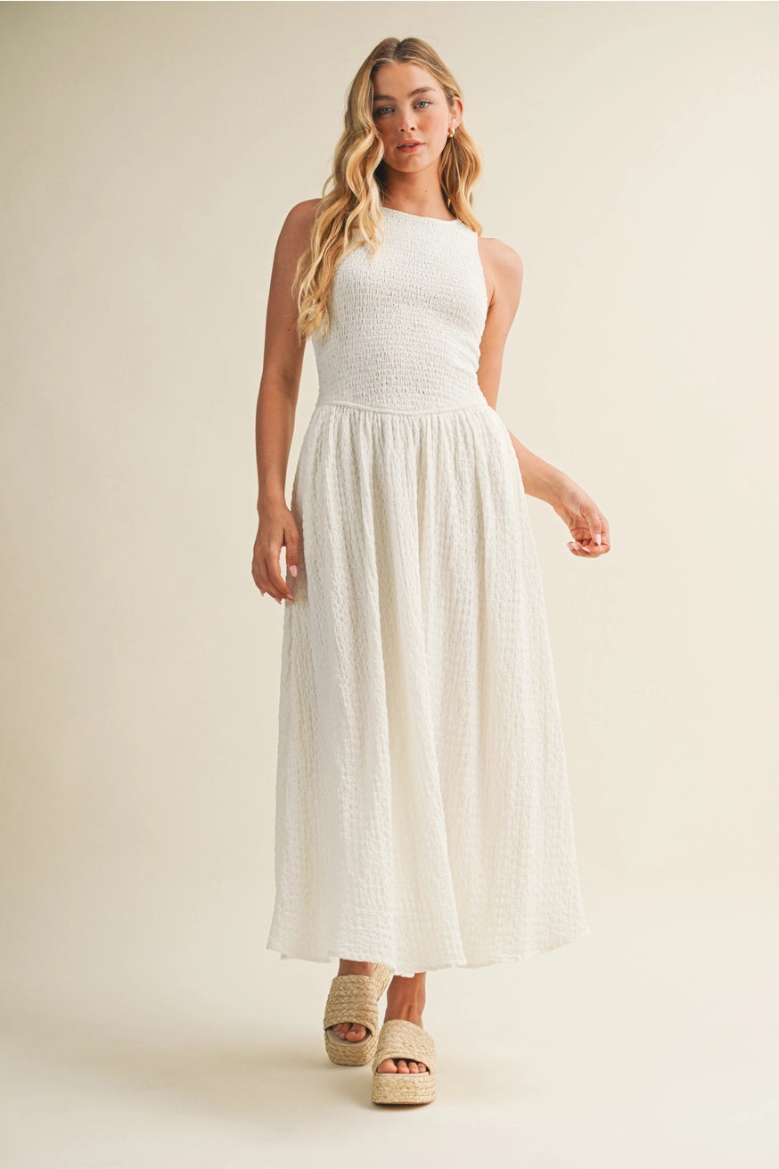 Woman wearing a white dress standing against a plain background