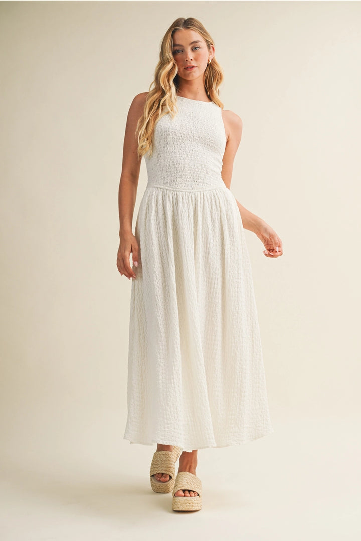 Woman wearing a white dress standing against a plain background