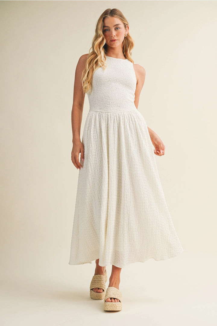 Woman wearing a white sleeveless dress against a plain background