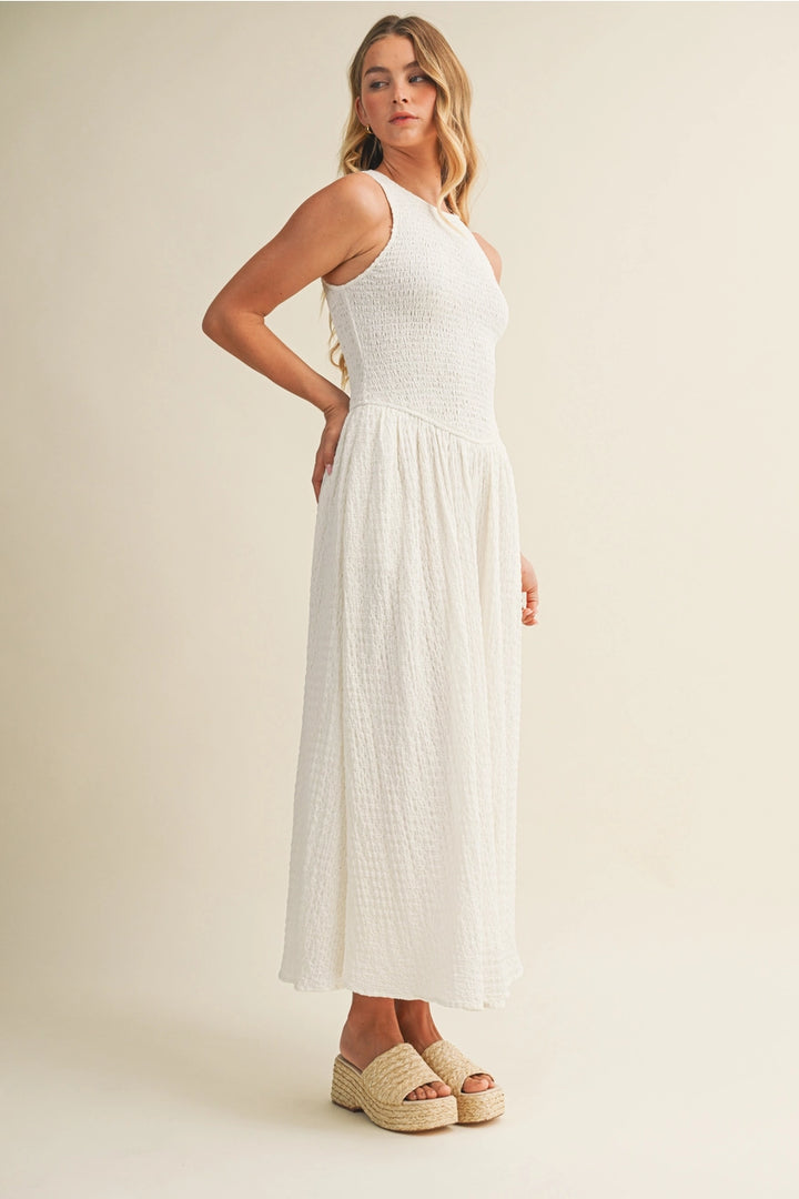 Woman wearing a white dress standing against a plain background